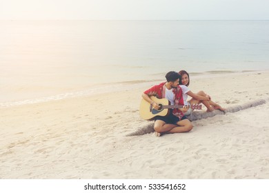 Romantic young couple playing a guitar on the beach - Powered by Shutterstock