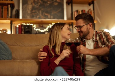 Romantic young couple relaxing at home and drinking red wine - Powered by Shutterstock
