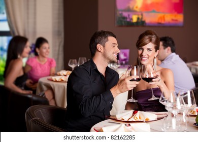romantic young couple at restaurant table toasting