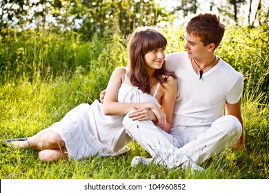 Romantic Young Couple Sitting In A Field