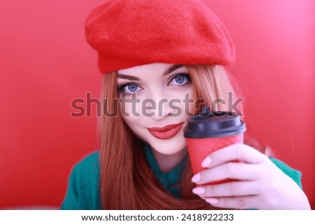 Romantic young woman holding a paper red cup with coffee or tea. red-haired girl in a bright red headdress.