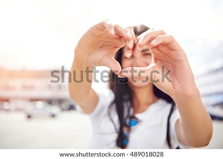 Romantic young woman making a heart gesture as a symbol of her love for her sweetheart or as a flirting teasing sign