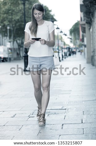 Similar – Woman with earphones listening music in smartphone