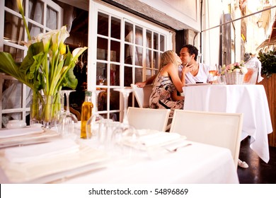 A Romatic Couple Kissing In An Outdoor Restaurant