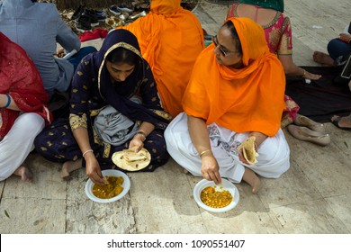 Rome, Italy, 04/15/2018: two Sikh women eat Dahl during the Nagar Kirtan celebrations.Nagar Kirtan is a religious procession that takes place wherever there are Sikh communities during April