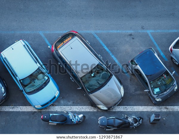 Rome, Italy - 06 27\
2018: Capital of Italy. The street in Rome is full of cars. The\
problem of parking places. Lack of parking space. Carelessly parked\
scooters. Top view.