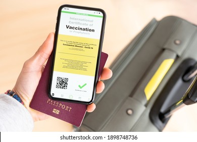 Rome, Italy, 20 January 2021. Overhead View Of An Human Hand Holding A Passport And A Smart Phone With A Digital Illustration Of A Certificate Of Vaccination Against The Covid-19 Disease.