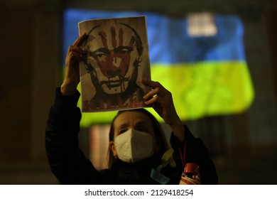 ROME, ITALY, 25.02.2022: Woman holds poster with Putin face bloody during Ukrainian protesters with candles gather in Piazza del Campidoglio in Rome, against the war operations of Russia in Ukrainian
