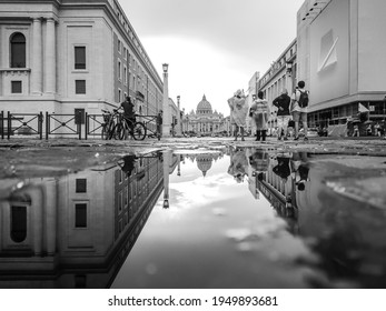 Rome, Italy - August 18, 2019: Black and white view on Vatican City St. Peter's Basilica with mirror reflection in water on city street. Epic grayscale scene