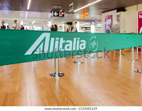 Rome, Italy, July 2019: green ribbon\
barrier with the Alitalia airline logo inside the Leonardo da Vinci\
international airport in Rome Fiumicino,\
Italy