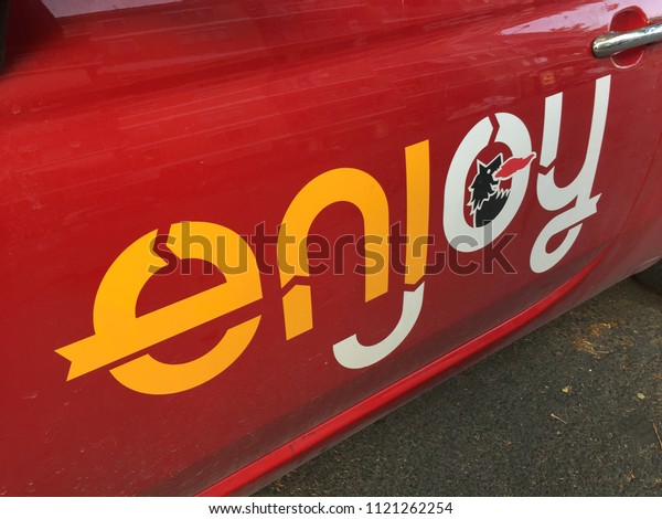 Rome, Italy - June 10, 2018: Enjoy logo. Enjoy is\
an Italian car sharing service provided by Eni. The system offers\
exclusively Fiat 500 vehicles with one-way point-to-point rentals\
charged by minute