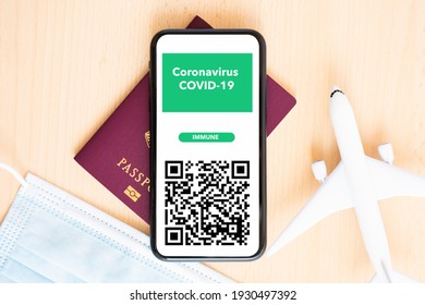 Rome, Italy, March 06, 2021.  A Face Mask, Model Airplane, Passport And A Smart Phone With A Coronavirus, COVID-19 Immunity Pass Are Arranged On A Wooden Background. 