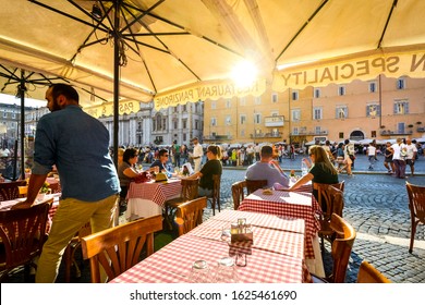 Rome, Italy - September 16 2019: Tourists Dine At A Romantic Italian Restaurant As The Sun Goes Down And They Watch The Activity In Piazza Navona In Rome Italy