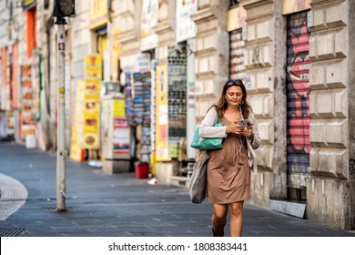 Rome, Italy - September 4, 2018: One Woman In City Street Walking On Sidewalk Listening To Phone Headphones By Historic Wall In Downtown Old Town