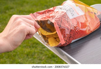 Romsey, UK - June 09 2021. Close Up Of An Unidentifiable Human Hand Reaching In To A Packet Of Crisps With Intentional Selective Focus, Shallow Depth Of Field And Bokeh