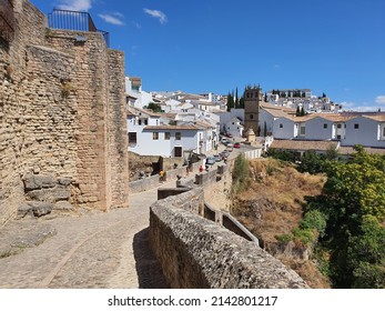 Ronda, Spain - 08 29 2021: 'El Tajo' canyon with historical old bridge 'Puente Viejo', white houses and catholic church 'Iglesia de Padre Jesús'.