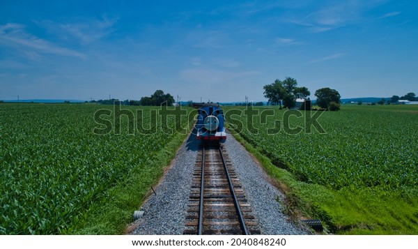 RONKS, UNITED STATES - Jun 29, 2019: A Thomas the\
tank engine pulling passenger cars and blowing smoke on a beautiful\
sunny day in Ronks