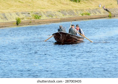 RONNEBY, SWEDEN - JUNE 13, 2015: Sillarodden, a rowing contest from sea to town to sell herring. Three senior men struggle on the finale stretch.