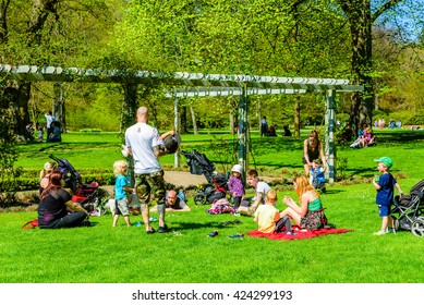 Ronneby, Sweden - May 8, 2016: People Enjoying The Fine Weather While Relaxing In The Park. Young Adults And Children Playing And Resting On Blankets In The Green Grass. Real People In Everyday Life.