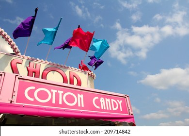 The Roof Of A Carnival Cotton Candy Sale Stand Has Colorful Flags On It In Front Of A Blue Sky.