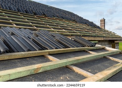 Roof ceramic tile arranged in packets on the roof on roof battens. Preparation for laying tiles on a boarded roof. - Shutterstock ID 2244659119