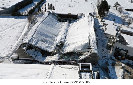 Roof collapsed under the weight of snow. Aerial view of damaged falling roof inside a publica city area. Large collapsed condominium or industrial company. View from above with a drone.	