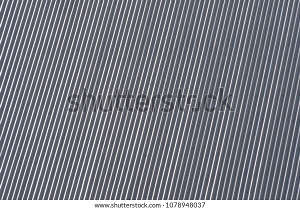 Roof\
cover textured metal roofing. Diagonal linear striped shiny\
building corrugated texture under the sun\
light