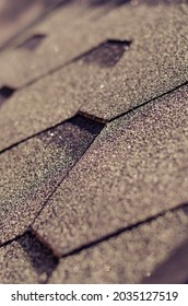 The Roof Is Covered With Asphalt Shingles Close-up.  Shingles - Roofing Material Based On Fiberglass, Modified Bitumen And Stone Sprinkles. Selective Focus, Blur, Noise, Grain Effect.