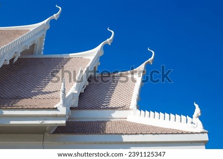 roof with decoration of the Buddhist white temple Wat Sawang Arom against the sky.