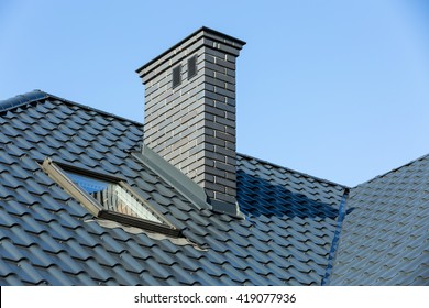 Roof of a detached house with a skylight and chimney against the sky