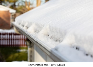 Roof Gutter Full Of Snow And Ice After Winter Storm. Concept Of Roof Damage, Home Maintenance And Repair