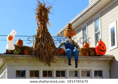 Roof of a house decorated for Halloween with corn, pumpkins, scarecrows and a ghost