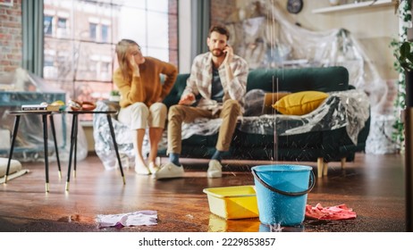 Roof is Leaking, Pipe Rupture at Home: Water Drips into Buckets in Living Room. Angry Couple in Background Calling Insurance Company, Screaming into Phone in Frustration, Trying to Find Plumber - Shutterstock ID 2229853857