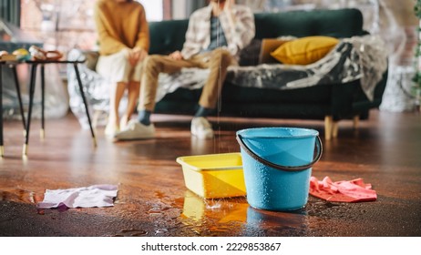 Roof is Leaking, Pipe Rupture at Home: Water Drips into Buckets in Living Room. Angry Couple in Background Calling Insurance Company, Screaming into Phone in Frustration, Trying to Find Plumber - Shutterstock ID 2229853867
