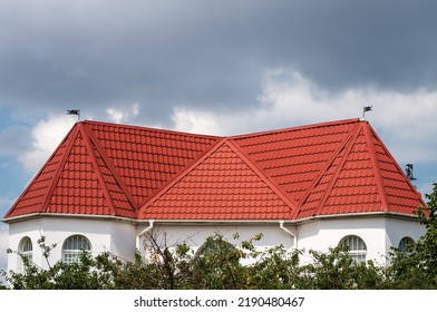 Roof Made Of Light Brown Red Metal Tile, Metal Roofing Shingles Against Blue Sky. 