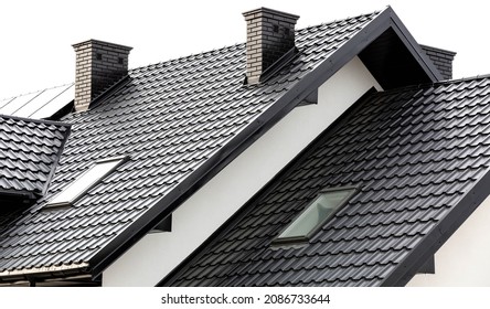 Roof of a new home. Ceramic chimney, metal roof tiles, gutters, roof window. TV antennas attached to the chimney. Single family house.