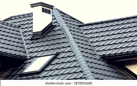 Roof Of A New House With Slants, A Skylight, A Plastered Chimney And Ventilation Grilles. Roof Covering With Steel Tiles.