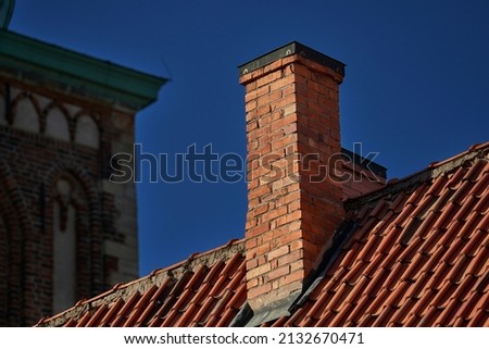 Roof on top of a house that's been tiled with light brown tiles. Ceramic tiles made from clay. Typical UK design and construction. Sunny Summer day. Vintage cottage on the seaside, in a coastal town.