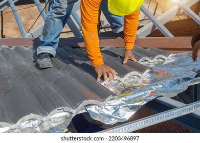 Roof Repair, Worker Replacing Gray Tiles Or Shingles On House With Blue Sky As Background And Copy Space, Roofing - Construction Worker Standing On A Roof Covering It With Tiles.