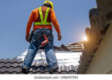 Roof Repair, Worker With White Gloves Replacing Gray Tiles Or Shingles On House With Blue Sky As Background And Copy Space, Roofing - Construction Worker Standing On A Roof Covering It With Tiles.