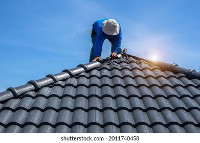 Roof Repair, Worker With White Gloves Replacing Gray Tiles Or Shingles On House With Blue Sky As Background And Copy Space, Roofing - Construction Worker Standing On A Roof Covering It With Tiles.