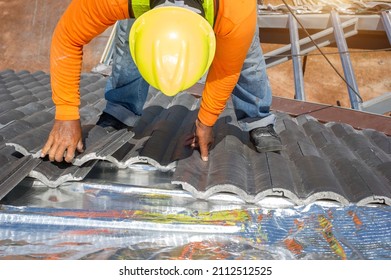 Roof Repair, Worker With White Gloves Replacing Gray Tiles Or Shingles On House With Blue Sky As Background And Copy Space, Roofing - Construction Worker Standing On A Roof Covering It With Tiles.