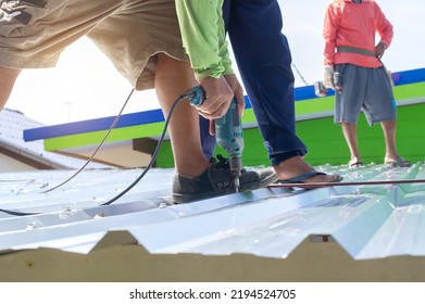 Roof Repair, Worker With White Gloves Replacing Gray Tiles Or Shingles On House With Blue Sky As Background And Copy Space, Roofing - Construction Worker Standing On A Roof Covering It With Tiles.