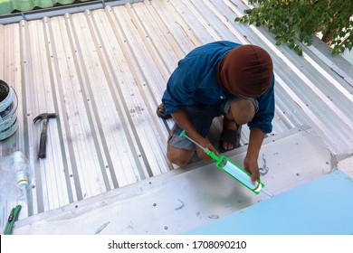 The Roof Repairman Is Firing Silicone To Fix The Roof Leaks. The Photo Is Used For The Advertisement Of The House Construction Business.