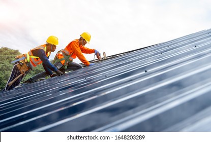 Roof Repairman Working On The Working At Height.Professional Industrial Climber In Helmet And Uniform Works At Height,Industrial Climbing At Construction Site,Working At Height Equipment Concept.