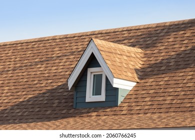Roof shingles with garret house on top of the house. dark brown asphalt tiles on the roof background with blue sky. - Shutterstock ID 2060766245