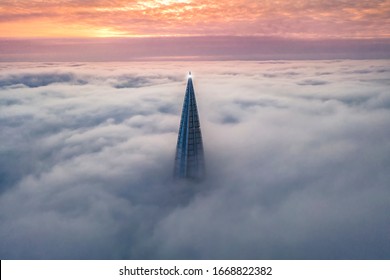 
the roof of the skyscraper and business center Lakhta center is visible above the clouds during sunset