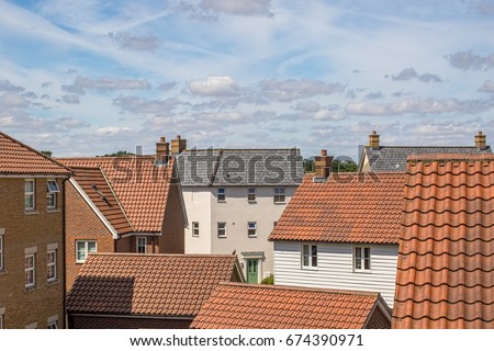 Roof top view of modern urban housing estate. Bright cloudy day over new varied homes on crowded suburban residential area.