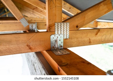 Roof trusses covered with a membrane on a detached house under construction, view from the inside, visible roof elements and truss plates.
