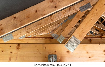 Roof trusses covered with a membrane on a detached house under construction, view from the inside, visible roof elements and truss plates.
